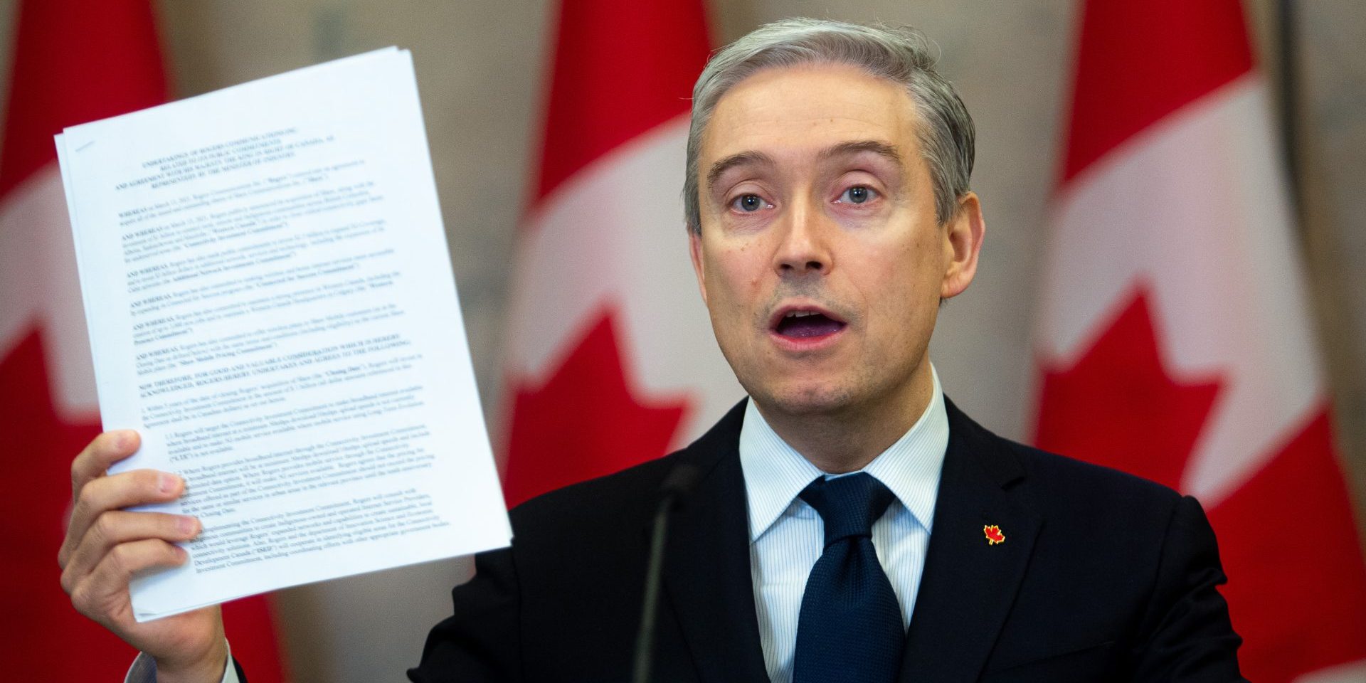 Minister of Innovation, Science and Industry François-Philippe Champagne holds up a contract between telecom providers and the federal government during a March 31, 2023, press conference in West Block to announce that the merger of Rogers and Shaw would proceed with conditions. The Hill Times photograph by Andrew Meade