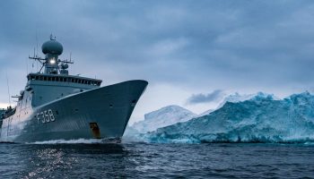 The Royal Danish Navy frigate HDMS Triton passes an iceberg in the waters around Greenland. Photograph courtesy of NATO/Flickr