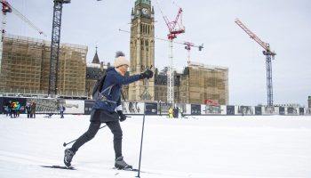 A person skis in front of Centre Block at Ski Day on the Hill on  Feb. 24, 2026. The Hill Times photograph by Andrew Meade