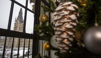 The MacKenzie tower is pictured from a window in the Wellington Building on on  Dec. 11, 2025, as Christmas decorations adorn the a tree inside. The Hill Times photograph by Andrew Meade