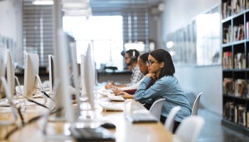 Shot of a group of university students working on computers in the library at campus