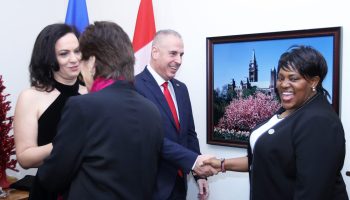 Alina-Victorita Manoiu, left, with her husband Ambassador Manoiu, who shakes the hand of Kenya's High Commissioner to Canada Carolyne Kamende Daudi. The Hill Times photograph by Sam Garcia