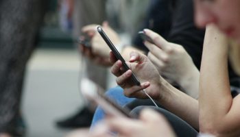 People on phones stock photo. Photograph courtesy of Unsplash/Robin Worrall